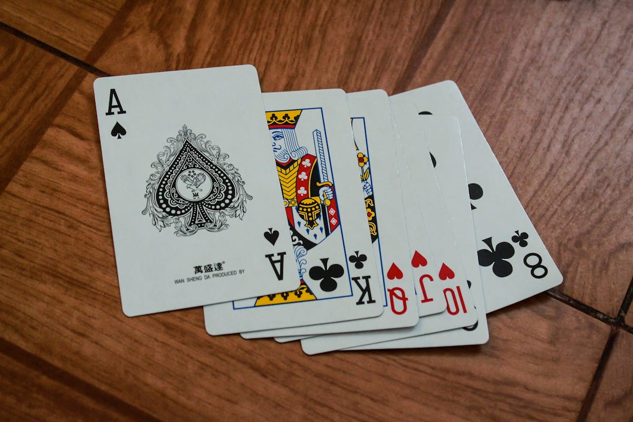 A close-up view of playing cards on a wooden surface, featuring an ace of spades.