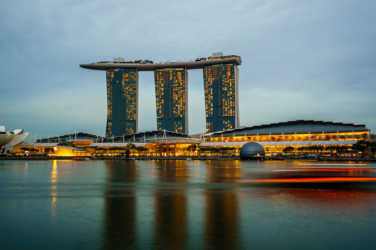 Marina Bay Sands illuminated at sunset in Singapore, reflecting on calm waters.